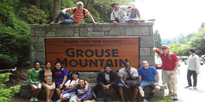 a group of people siting around a Grouse Mountain sign